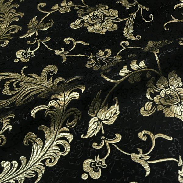 Black brocade fabric with golden green peacock feathers and floral design